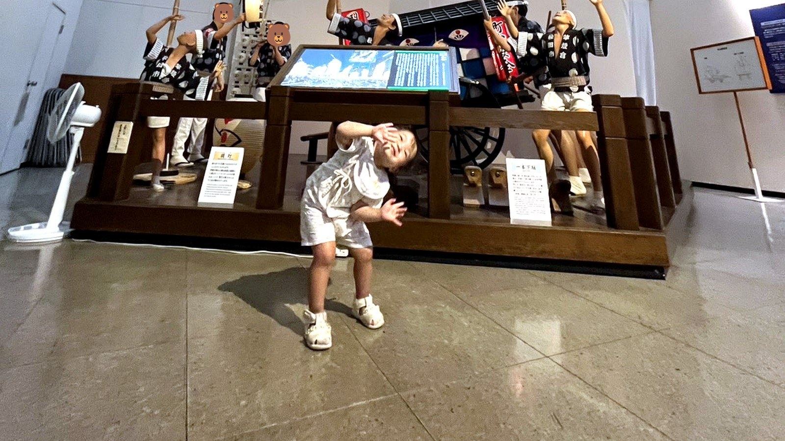 竿燈の展示の前でポーズをとる子供